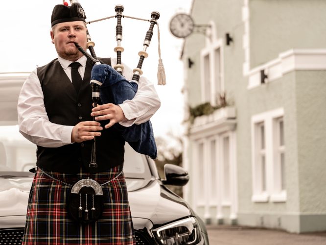 man in quilt and playing the bag pipes